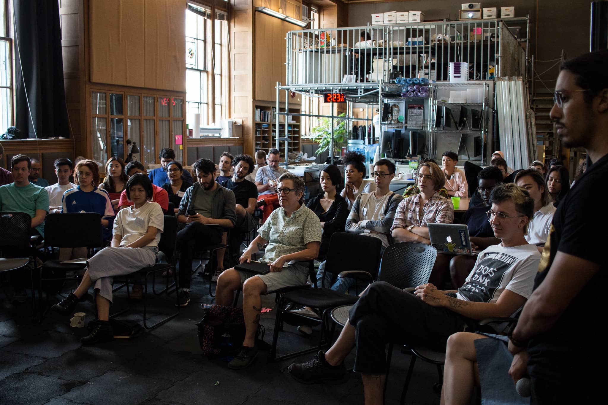 Participants sit in a classroom towards the speakers listening intently"